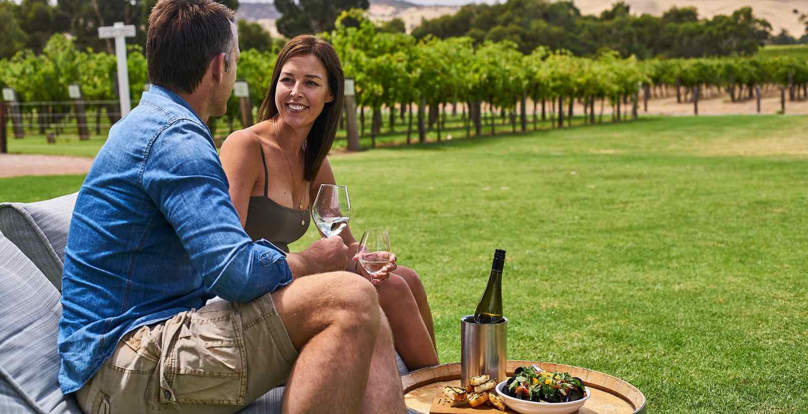 A mana and woman holding wine looking at each other
